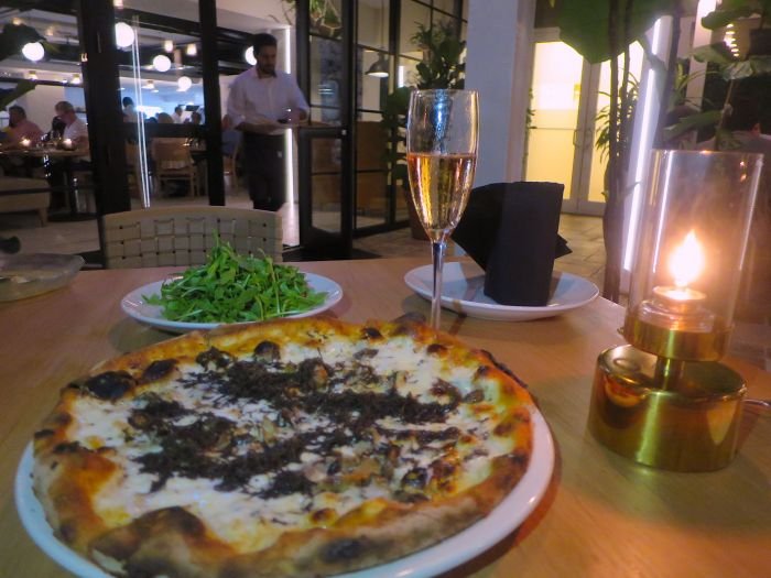 A plate of pizza and a glass of wine Description automatically generated