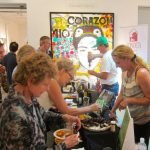A group of people standing in a kitchen preparing food Description automatically generated